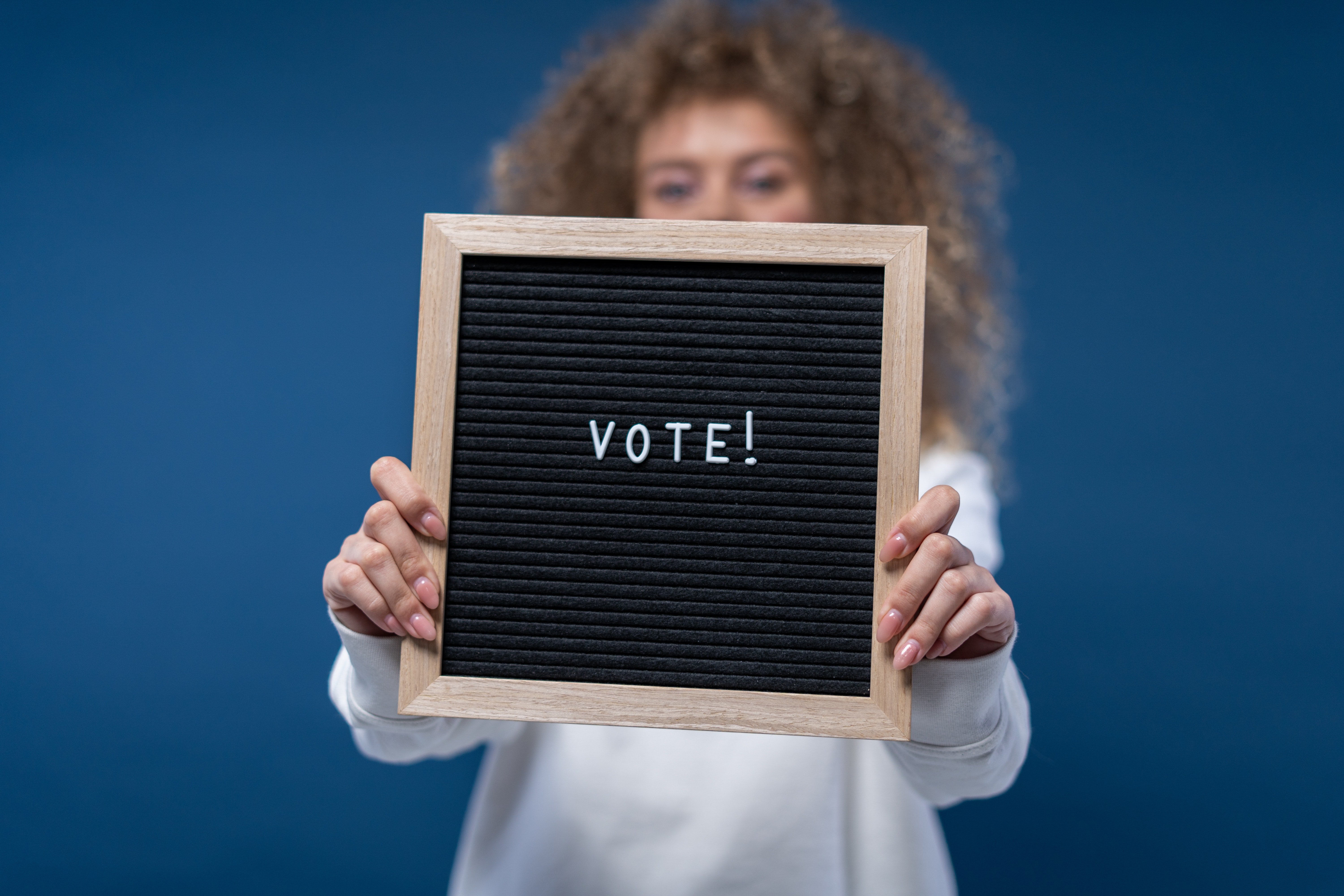 Image of a girl with a blackboard. It is written the word VOTE in the blackboard