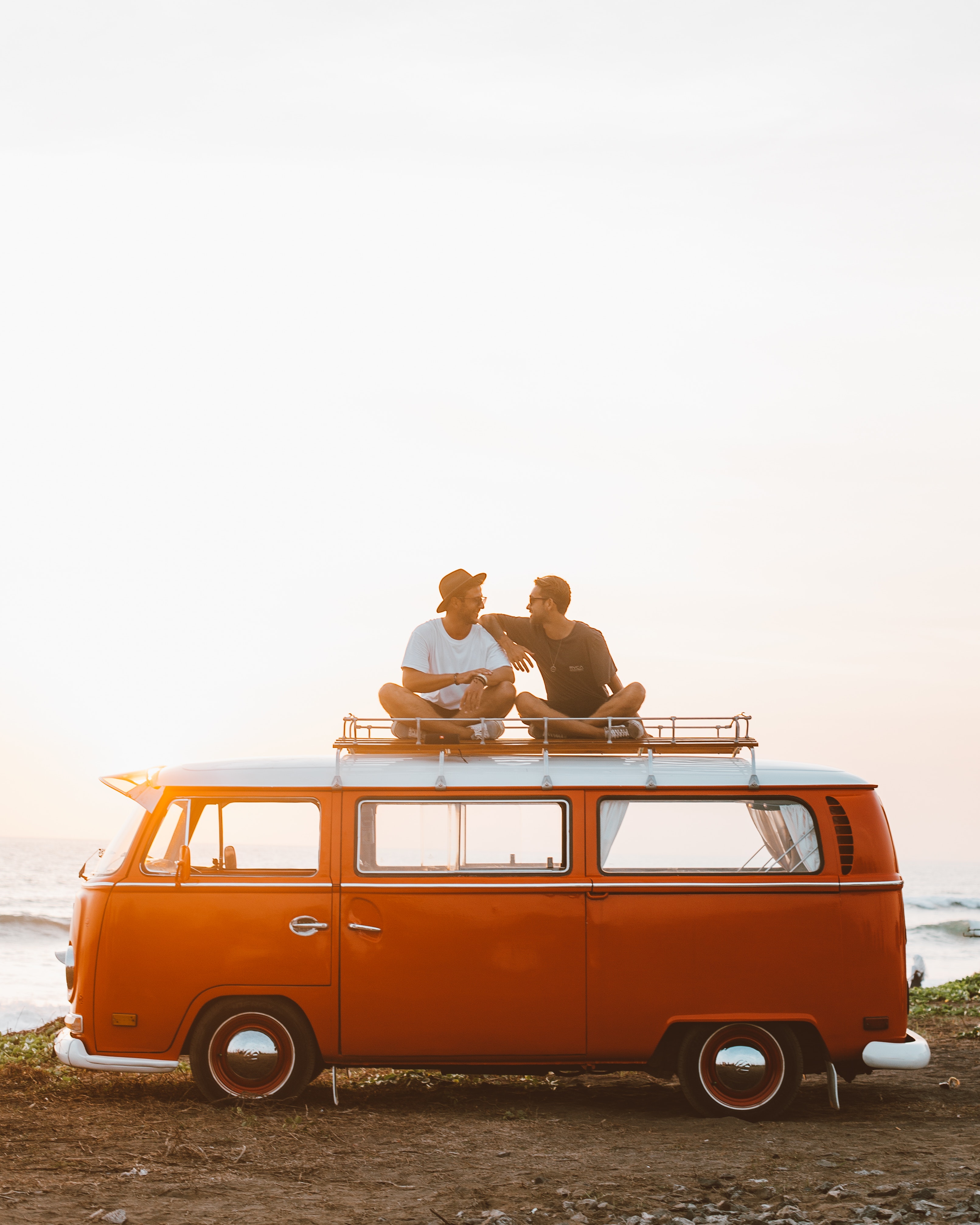 Two friends smiling sitting above a caravan