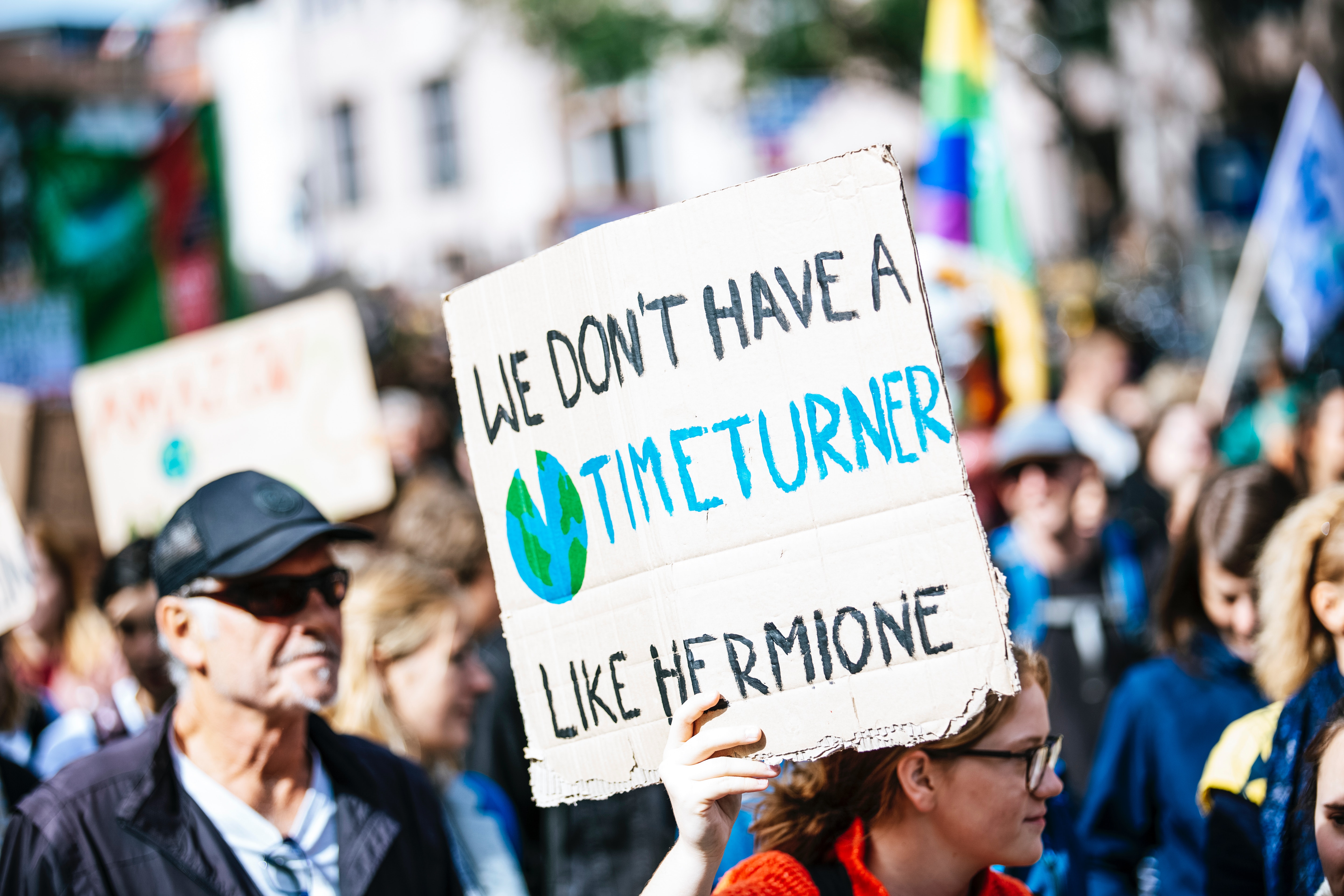 Image of a girl carrying a banner. It is written on the banner 'We dont have a timeturner like Hermione'
